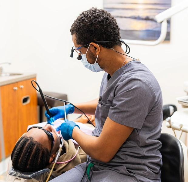 Dentist in blue gloves examines patient's teeth in modern dental office setting.