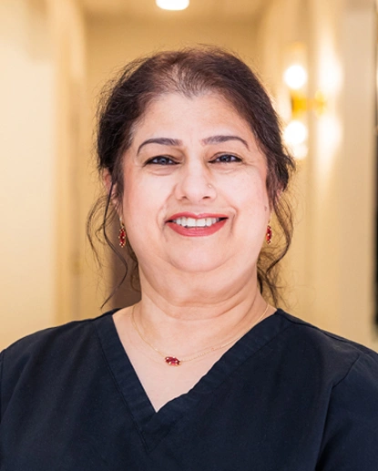 Professional headshot of smiling woman in black scrubs at dental office.