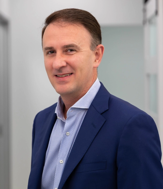 Professional male dentist in blue blazer smiling at dental office